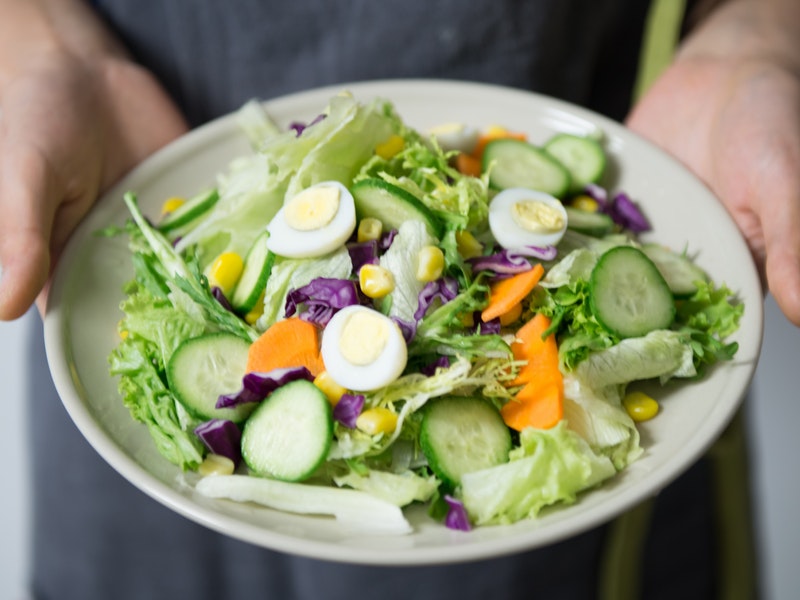 mani reggono piatto di insalata dietetica